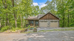 A cabin with a stone exterior, a garage, and a picnic table in front. - Silver Linings - Hot Tub, Mountain Views, Close to Town, Pet Friendly (Waynesville)