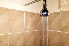 A shower with a horizontal bar and a vertical spout, set against a tiled wall.