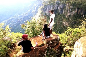 A group of people on a rocky outcrop overlooking a steep cliff with dense vegetation.