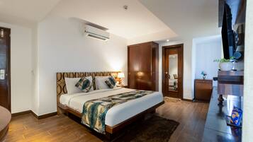 A modern bedroom with a large bed, wooden wardrobe, and a flat-screen TV.
