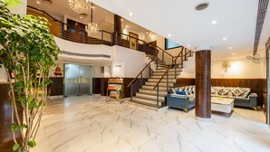 A spacious lobby with a marble floor, a staircase, a reception desk, and a large plant. - Arch Plaza - Near Yashobhoomi Convention Centre Dwarka (New Delhi)