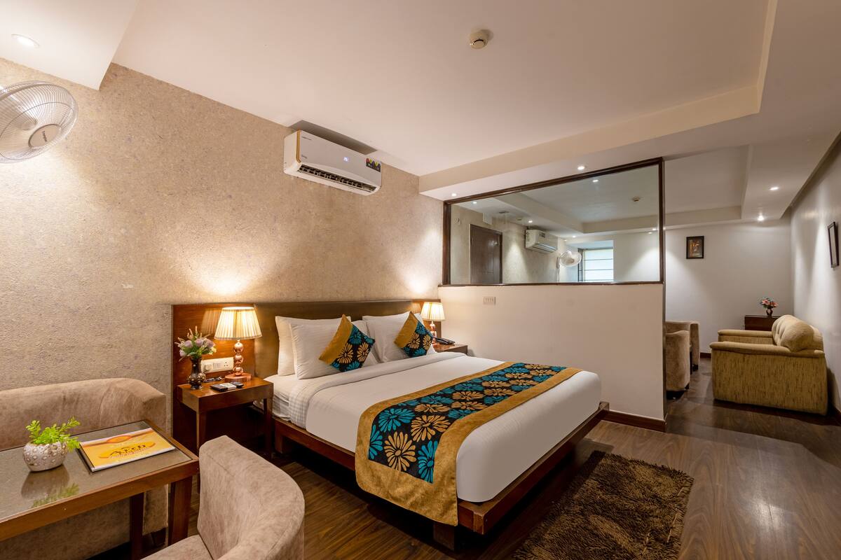 Une chambre d’hôtel avec un lit, une table de chevet, une lampe et un miroir.