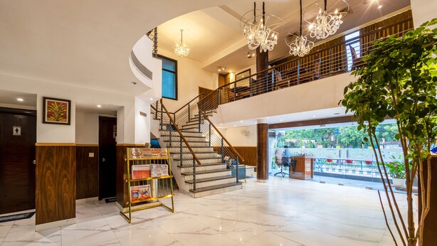 A hotel lobby with marble flooring, a staircase, chandeliers, and a reception desk. - Arch Plaza - Near Yashobhoomi Convention Centre Dwarka (New Delhi)