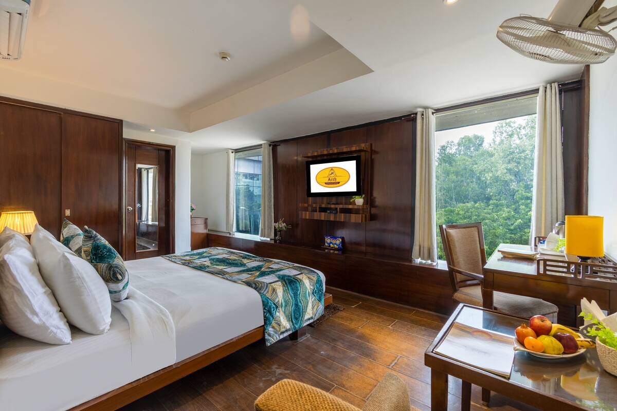 Une chambre d’hôtel avec un grand lit, un bureau avec une chaise, une télévision et une vue sur l’extérieur.