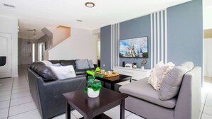 Una sala de estar moderna con dos sofás, una mesa de centro y un televisor en la pared.
