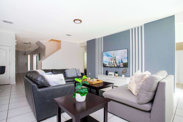 A modern living room with two sofas, a coffee table, and a TV on the wall.