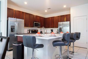 A modern kitchen with stainless steel appliances, wooden cabinets, and a central island with bar stools.