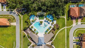 Vista aérea de una zona residencial con piscina central, varias casas y una glorieta.