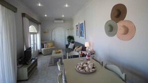 Un salon moderne comprenant un canapé, une table basse agrémentée d’objets décoratifs et un coin repas avec une table et des chaises.