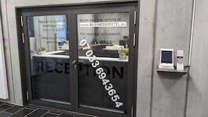 Et receptionsområde med en glasdør, en selvbetjeningscheck-in kiosk og en receptionsdisk.