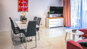 A modern living room with a dining area, a flat-screen TV, and a large window with curtains. - Cozy apartment in Lukecin with WiFi (Lukecin)