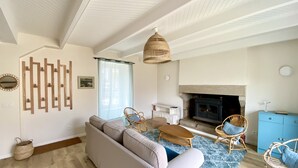 A living room with a sofa, chairs, a fireplace, and a blue rug. - Charming house in the port of Sainte-Marine (Combrit)