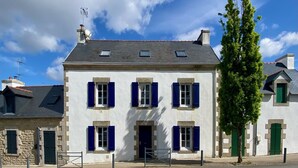 A two-story building with a white facade and blue shutters, featuring a central entrance and a small balcony. - Charming house in the port of Sainte-Marine (Combrit)