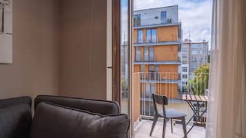 Un balcón con vistas a edificios modernos, una mesa de madera y dos sillas.