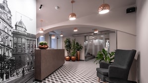Un vestíbulo moderno con una mesa de recepción, zona de estar y un mural grande de un edificio histórico.