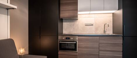 Una cocina moderna con armarios de madera oscura, horno integrado y pileta de acero inoxidable.