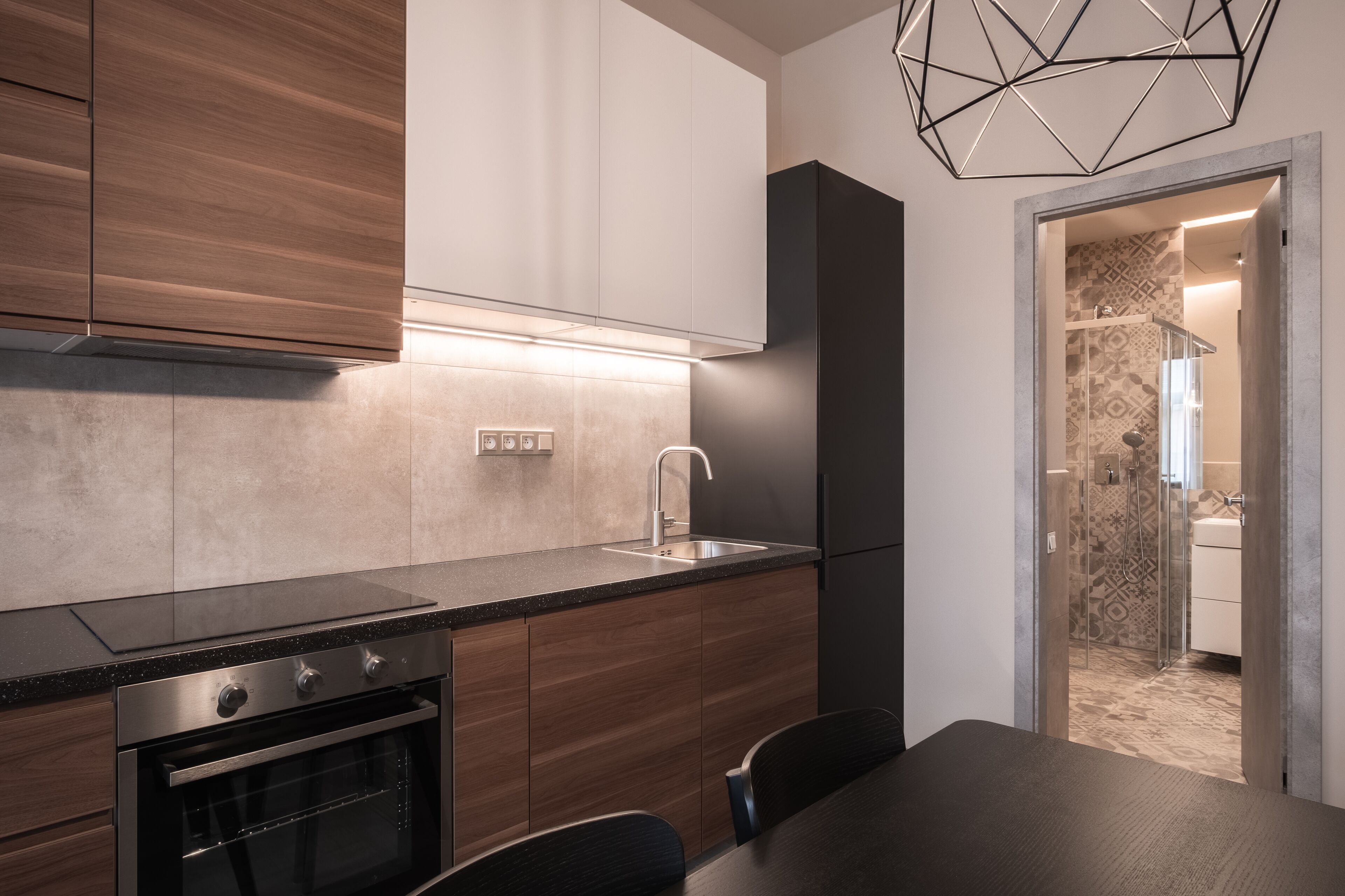 Une cuisine moderne avec des meubles en bois, un four encastré et un coin repas comprenant une table et des chaises.