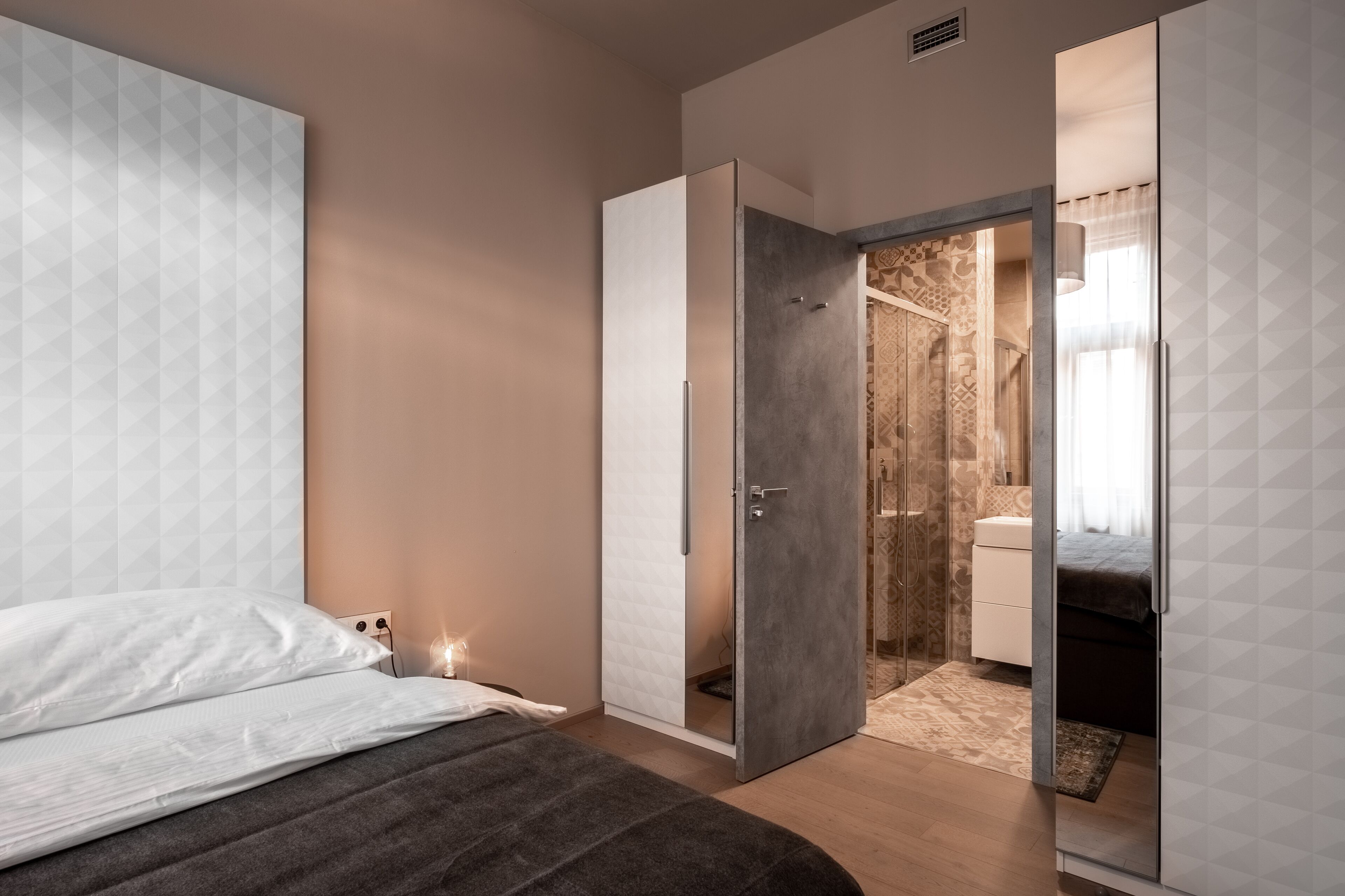 Une chambre à coucher avec un lit, une armoire et une salle de bain visible à travers une porte ouverte.