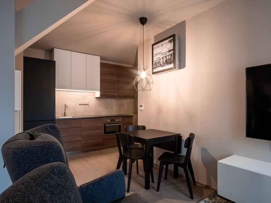 Una cocina moderna con armarios de madera, un comedor con mesa y sillas, y un televisor de pantalla plana montado en la pared.