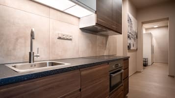 Una cocina moderna con un lavamanos de acero inoxidable, armarios de madera y una encimera negra.