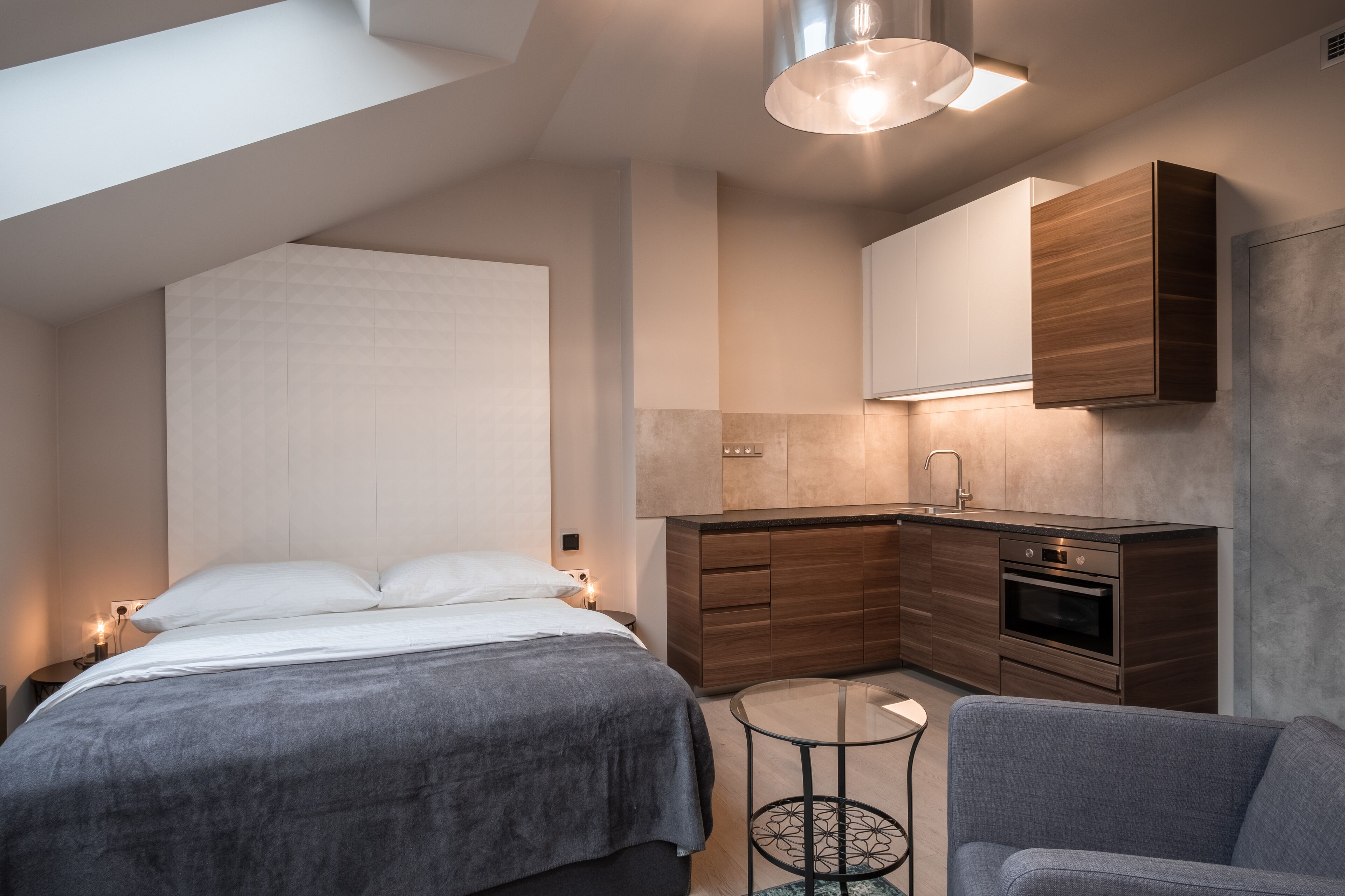 Un dormitorio moderno con una cama grande, una mesita redonda y un sofá.