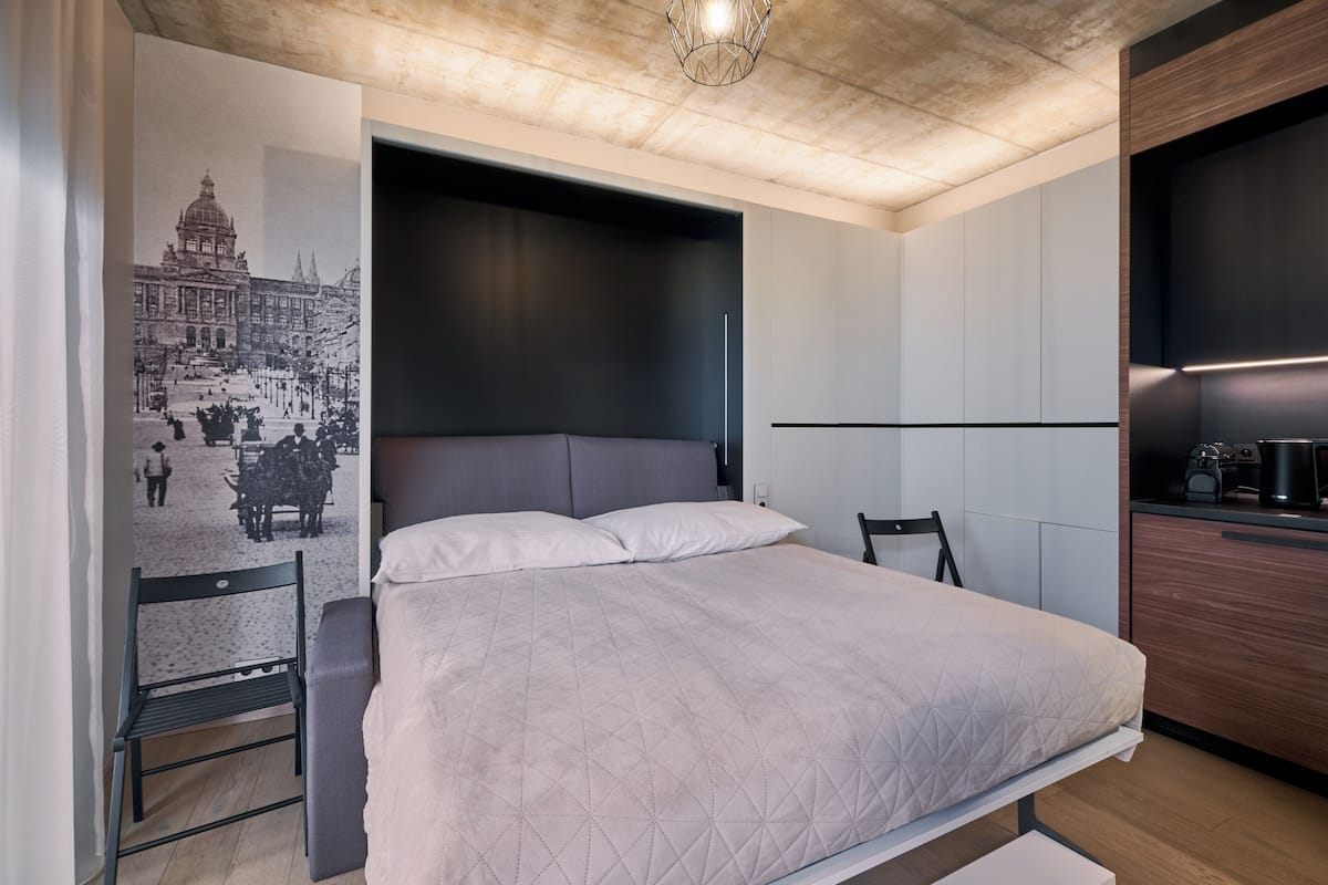 A modern bedroom with a large bed, a built-in bench, and a wall-mounted TV.