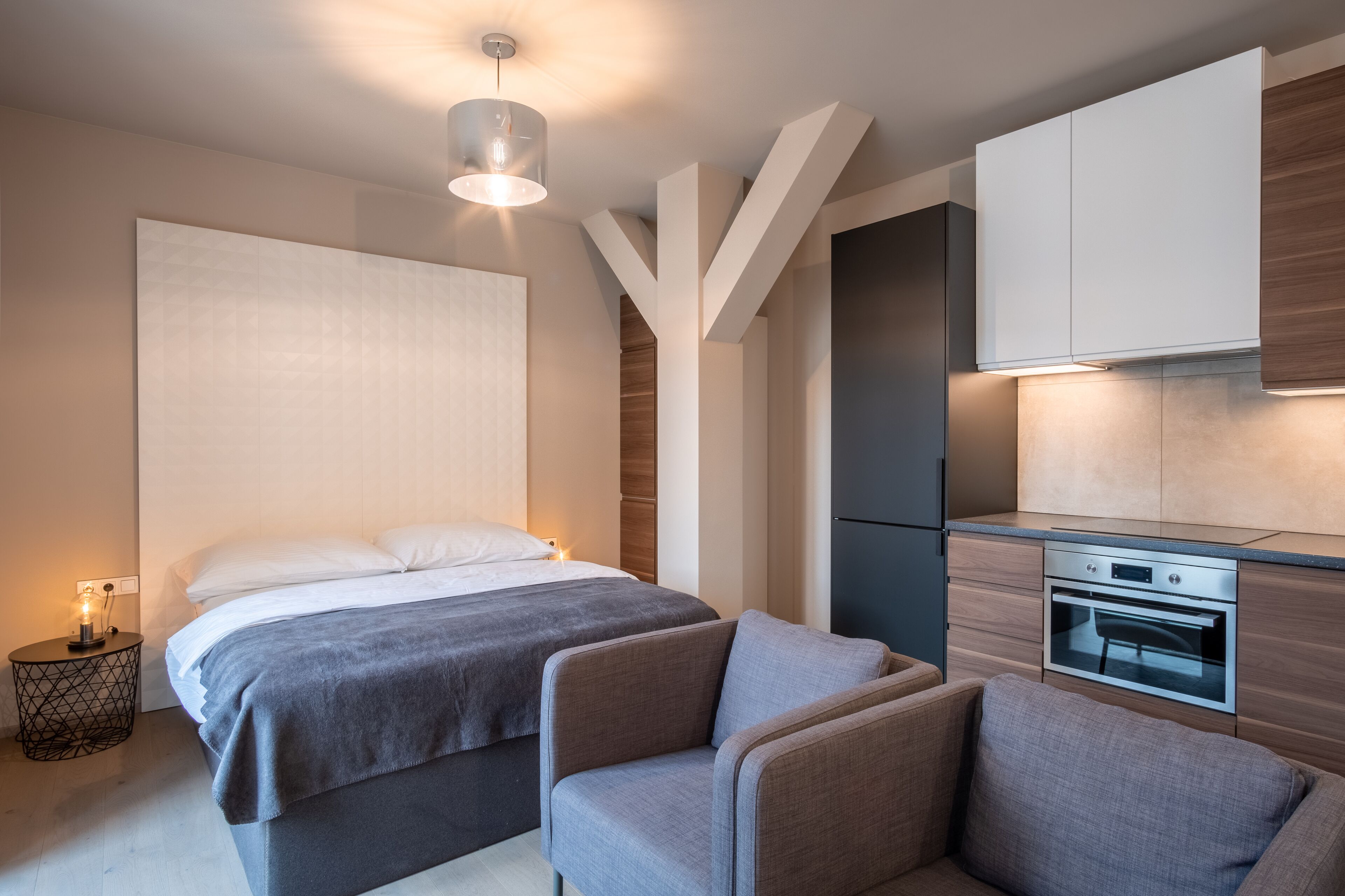 A modern bedroom with a large bed, bedside tables, and a built-in oven.