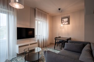 Uma sala de estar moderna com televisão de tela plana, uma mesa de jantar e um sofá.