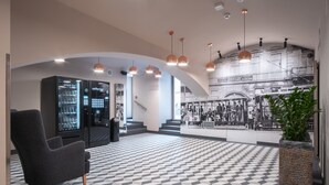 Un vestíbulo moderno con suelo a cuadros, máquinas expendedoras, una escalera y un mural.