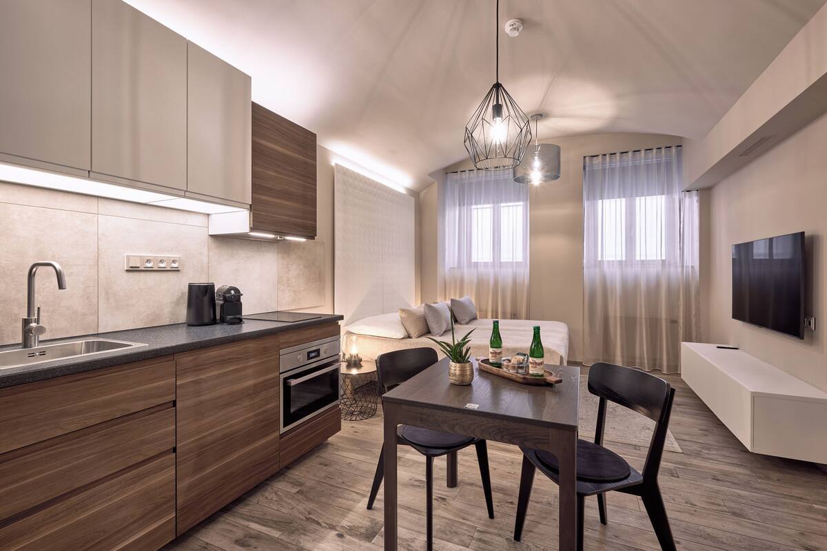 A modern kitchen with wooden cabinets, a built-in oven, and a dining area with a table and chairs.