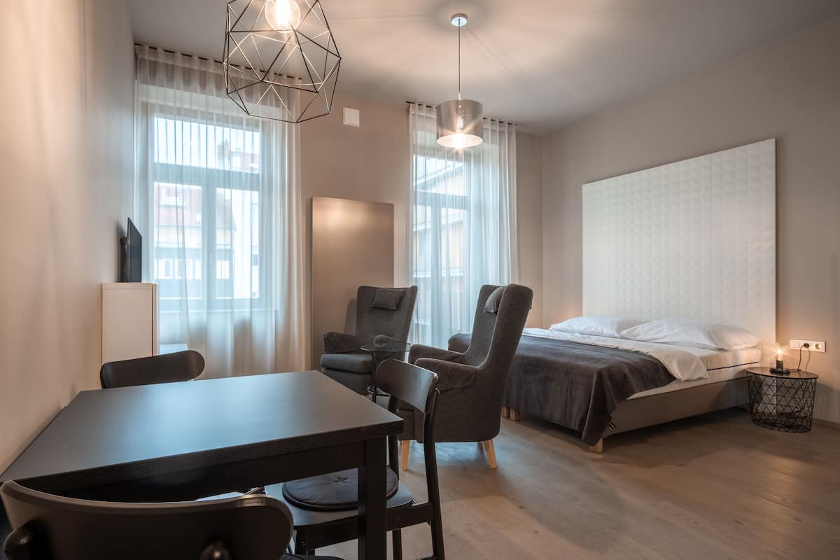 A modern bedroom with a bed, a desk, and two chairs.