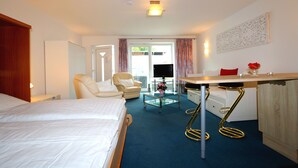 A hotel room with a bed, a chair, a small table, and a desk with a chair. - Studio Apartment With Terrace, own Parking Space and a Small Lake 500 m Away (Papendorf)
