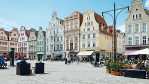 A historic square with cobblestone pavement, surrounded by colorful buildings with various shops and cafes. - Studio Apartment With Terrace, own Parking Space and a Small Lake 500 m Away (Papendorf)