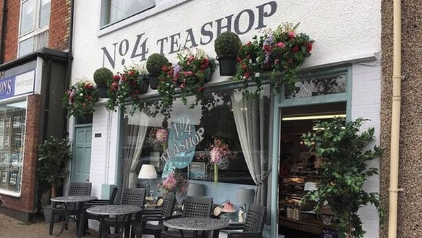 A storefront with a sign reading 'No.4 Teashop' and outdoor seating with tables and chairs.