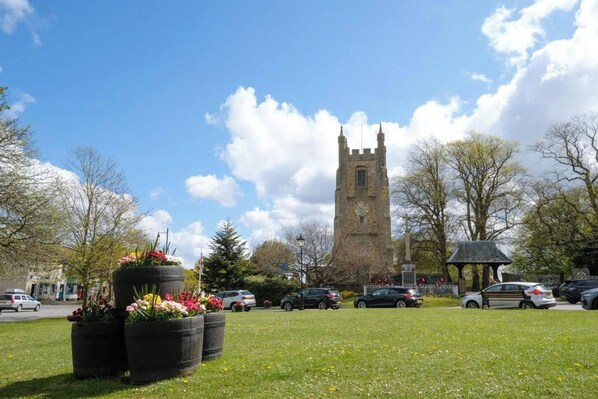A grassy area with flower planters, a tower, and parked cars. - Hardwick Haven, Sedgefield - Near Hardwick Hall (Stockton-on-Tees)