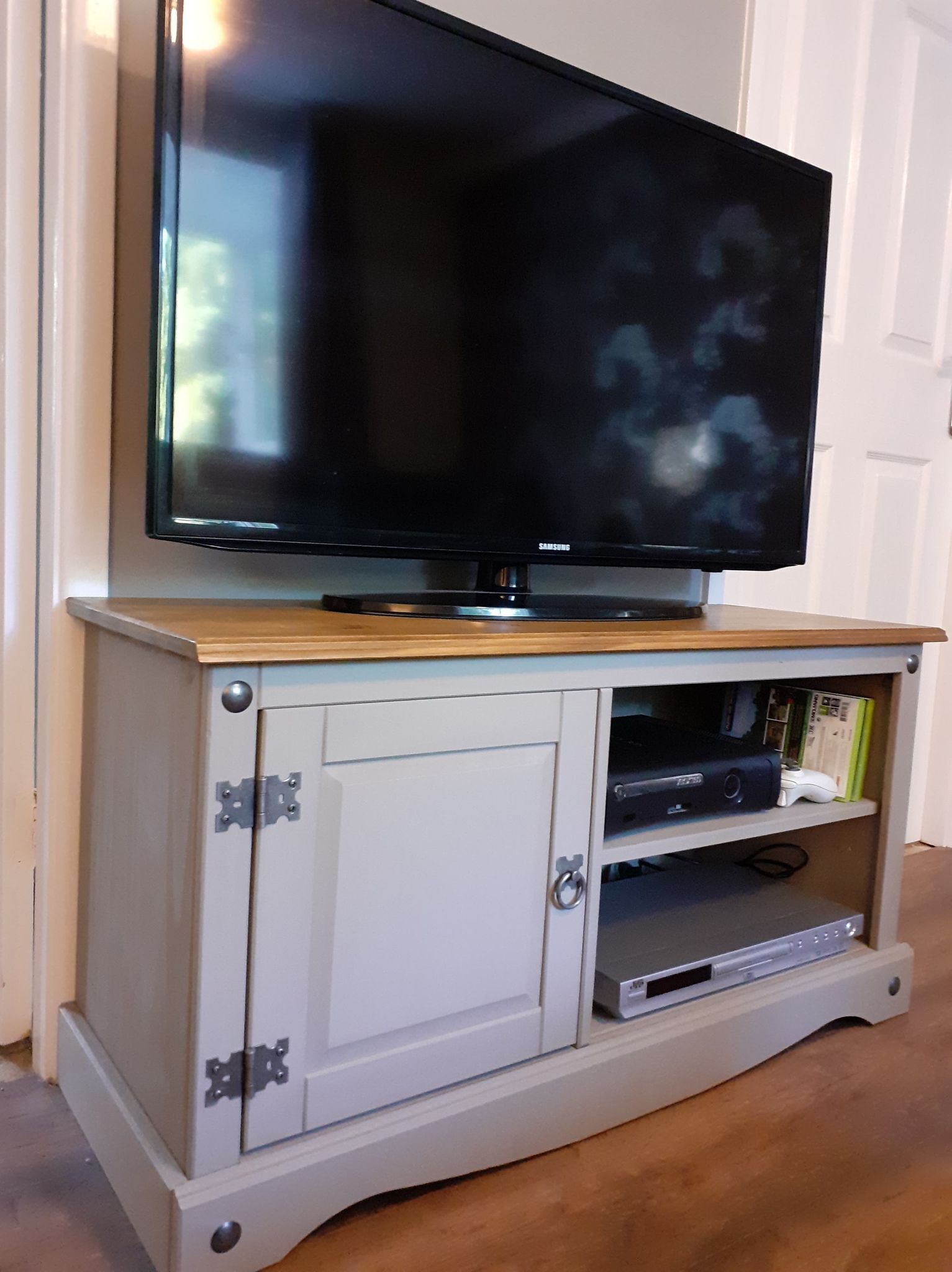 Un téléviseur posé sur un meuble en bois, avec une armoire blanche en dessous.