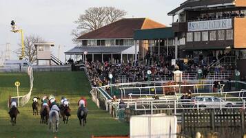 Un hippodrome avec des tribunes abritées, une foule de spectateurs et une piste délimitée par des clôtures.
