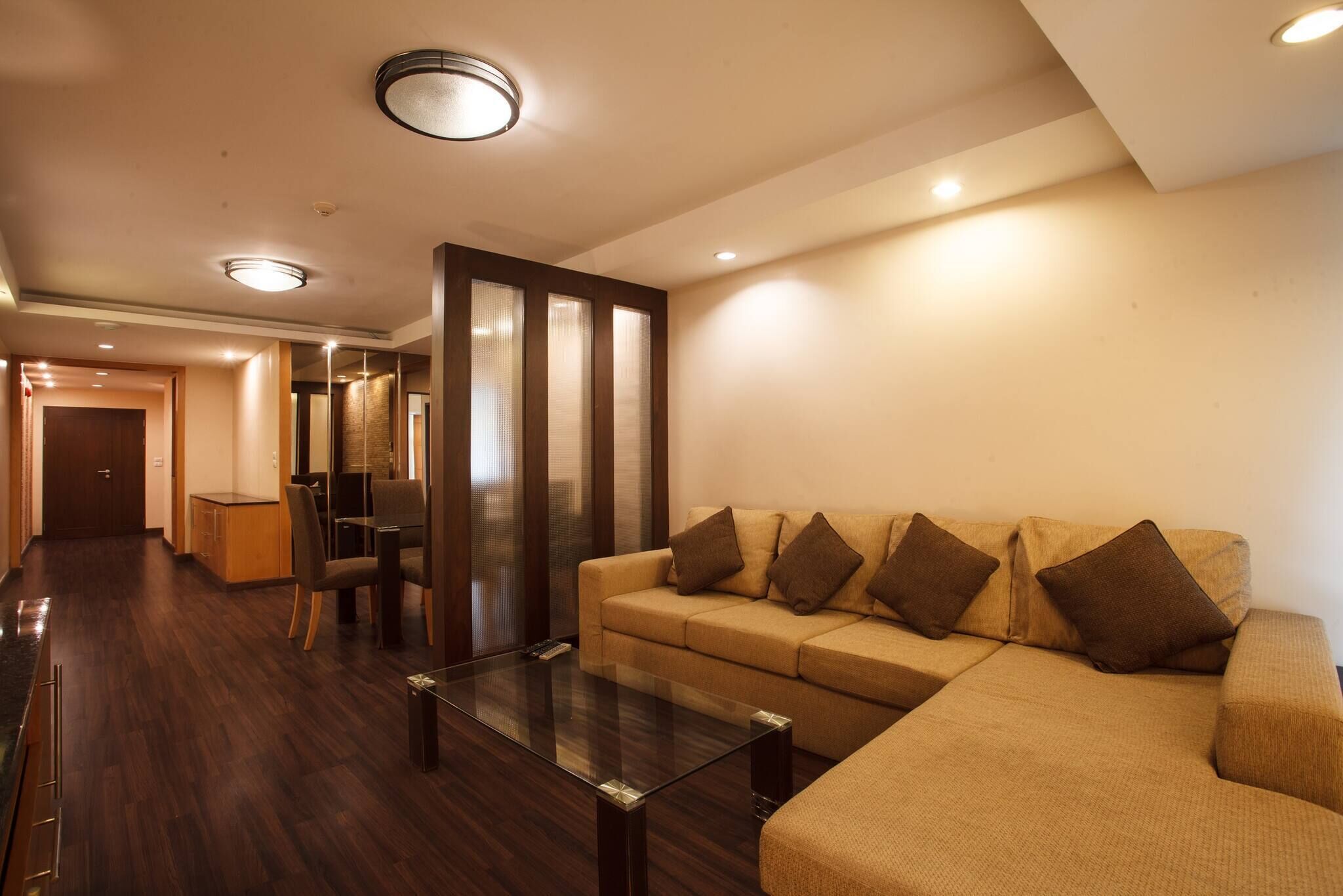 A modern living room with a sofa, a glass coffee table, and a dining area with chairs and a table.
