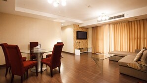 Een moderne hotelkamer met een zithoek, een bank, een televisie en een groot raam met gordijnen.