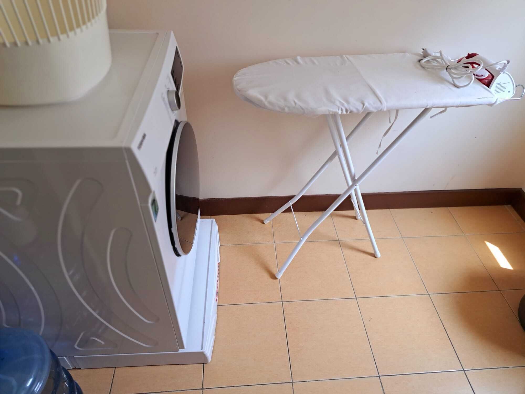 A laundry area with a washing machine and an ironing board.