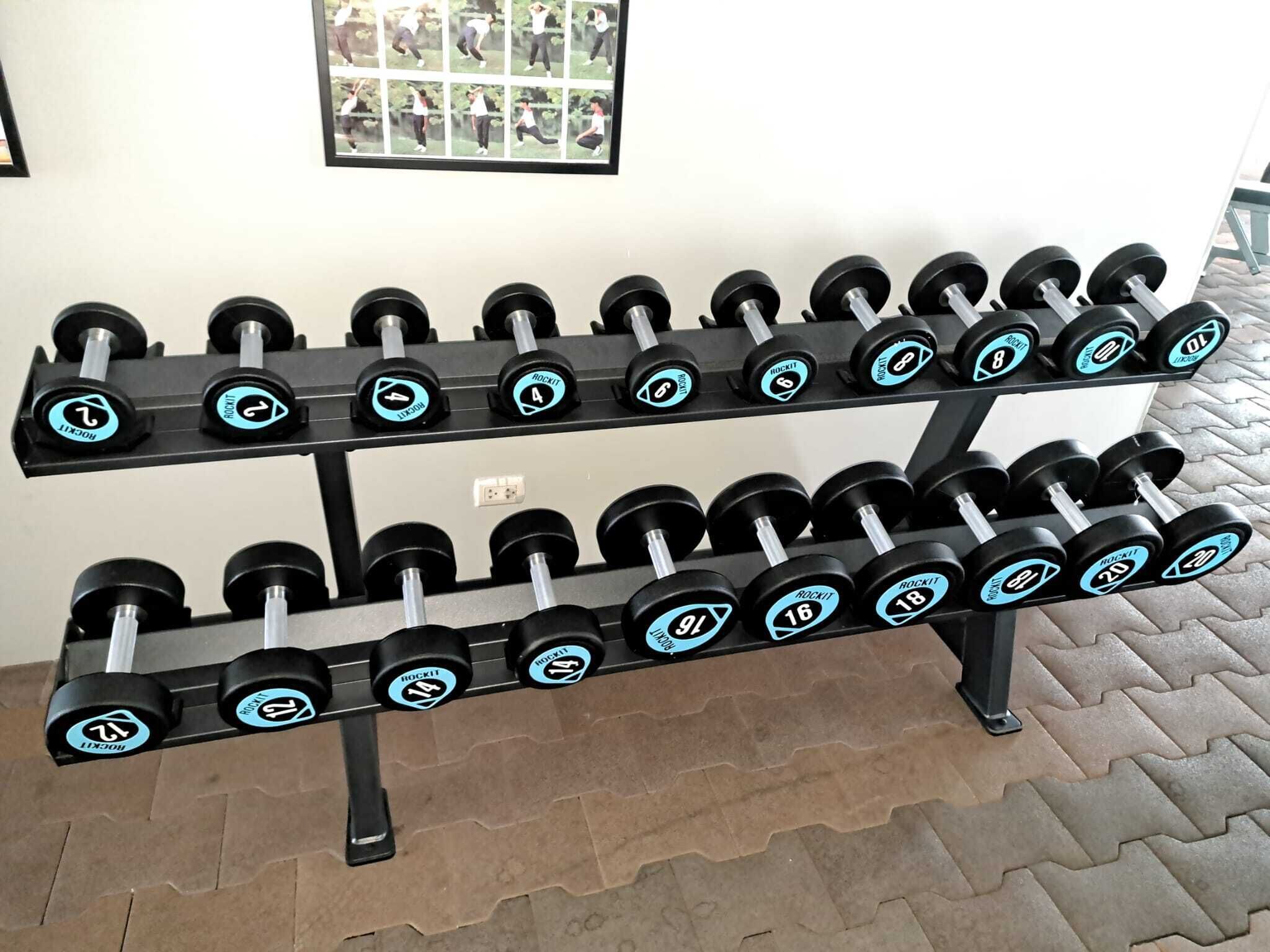 A rack of dumbbells with weight markings, positioned on a tiled floor.
