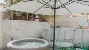 A hot tub under a canopy, a table with chairs, and a pool in a backyard setting. - Montereale Holiday Home (Realmonte)