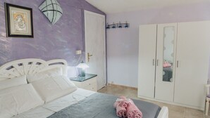 A bedroom with a bed, a nightstand, a lamp, a wardrobe, and a mirror. - Montereale Holiday Home (Realmonte)