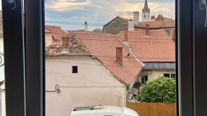 Uma carrinha amarela estacionada numa área residencial com uma igreja e um edifício com torre do relógio ao fundo.