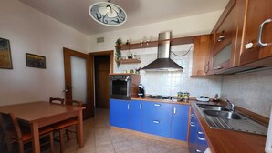 A compact kitchen with blue cabinets, a gas stove, and a stainless steel sink. - Belvedere House Noto Alta (Noto)