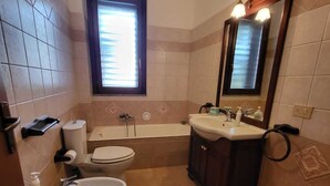 A bathroom with a toilet, bidet, sink, and bathtub. - Belvedere House Noto Alta (Noto)