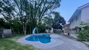 Un jardin avec une piscine, une terrasse en bois et une maison.