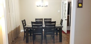 A dining area with a table and four chairs, a chandelier, and a door with a WiFi password sign.