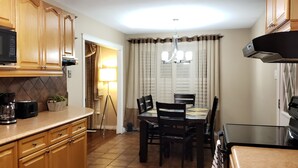 Une cuisine avec des meubles de rangement en bois, un four à micro-ondes, une machine à café et une table à manger avec des chaises.