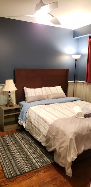 A neatly made bed with a striped bedspread, a wooden nightstand with a lamp, and a floor lamp.
